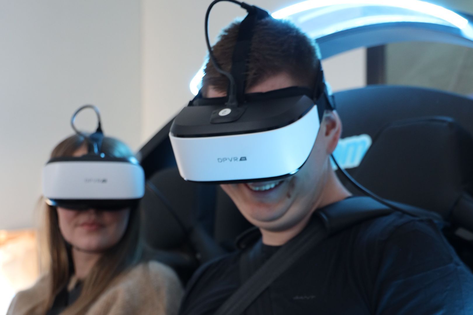 Mies janainen istuu vr-lasit päässä V-Roomin laitteessa hymyillen.